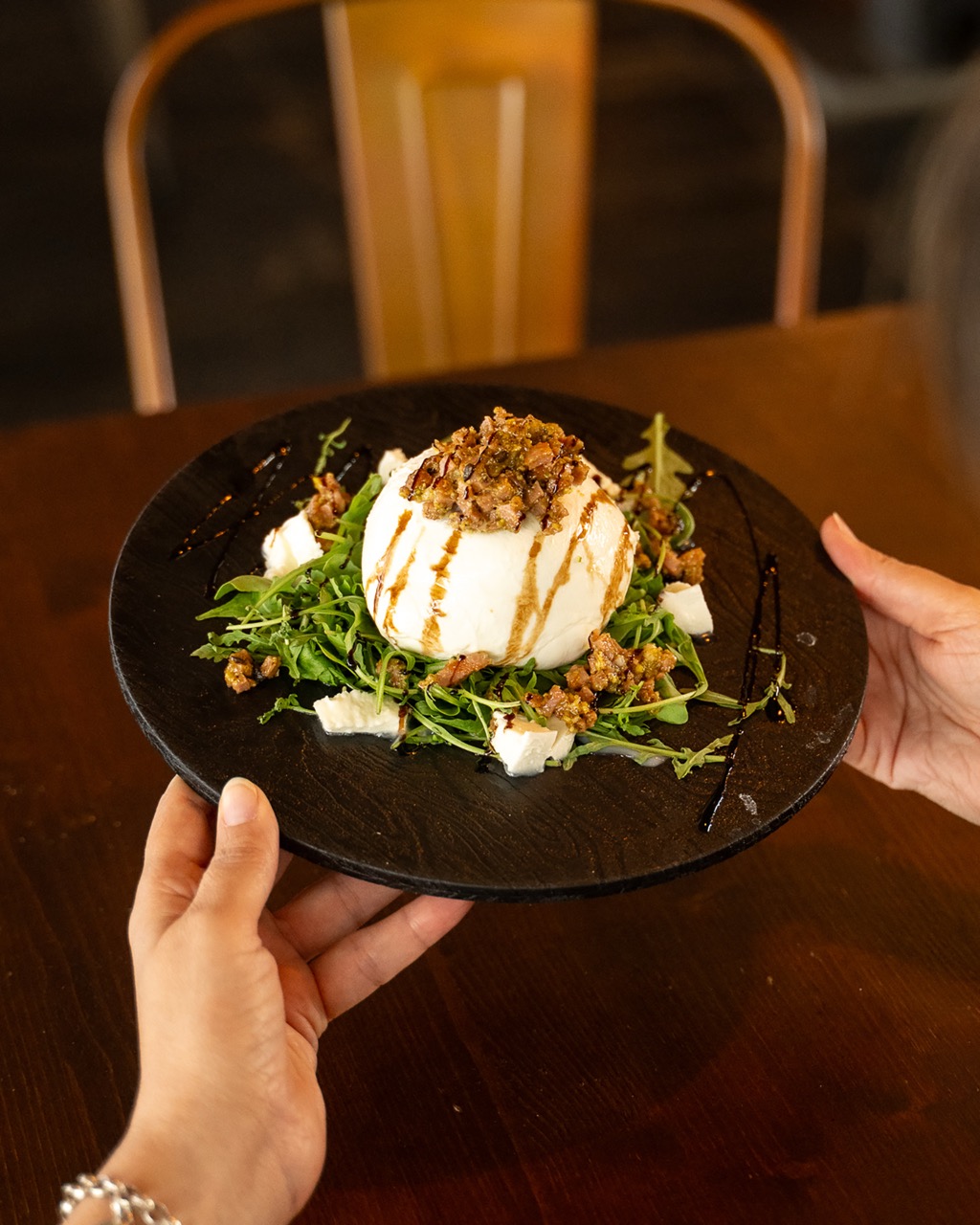 Burrata servita su letto di rucola con condimento