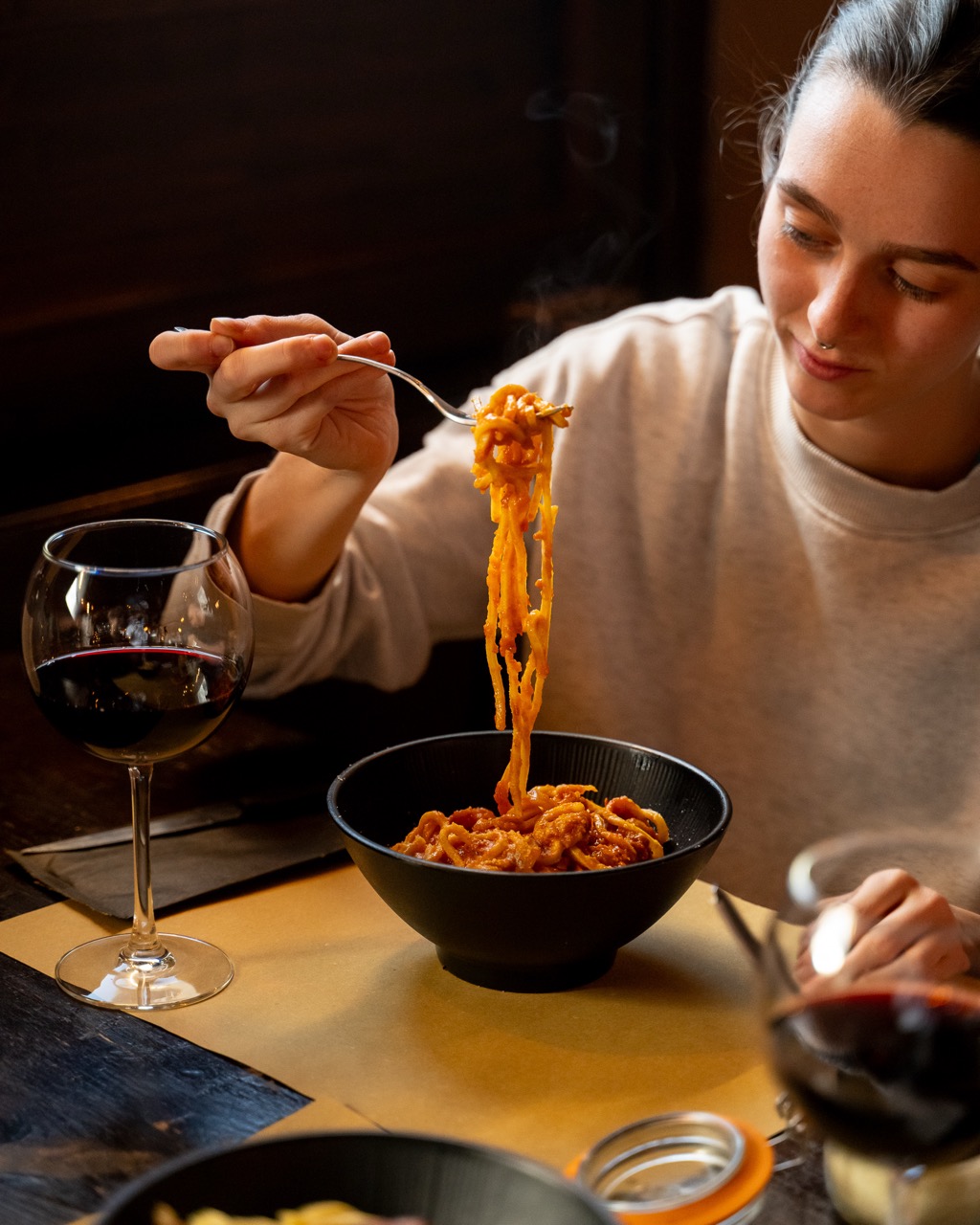 Piatto di pasta gustato in sala con calice di vino